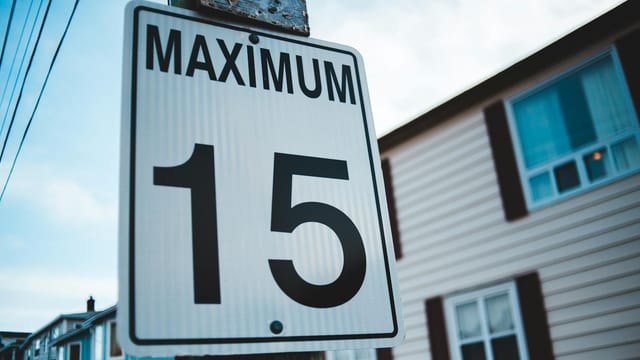 Regulatory road sign with Maximum inscription and number 15 against house facade in city in daytime