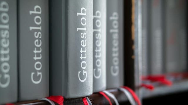 Macro shot of Gotteslob hymn books with red bookmarks neatly arranged on a bookshelf.