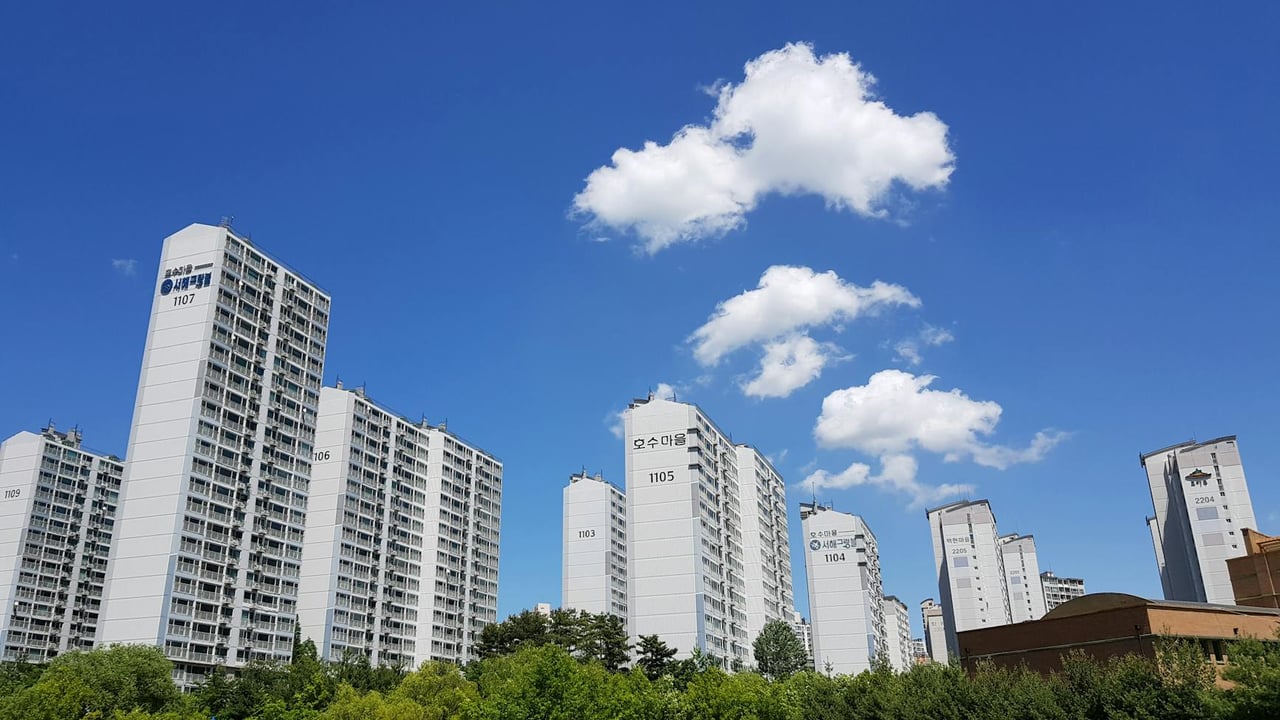 Skyline of high-rise apartments in Yongin with clear blue sky and clouds.