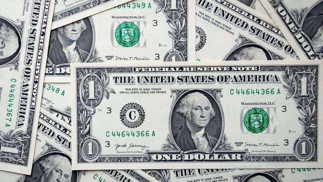 Detailed close-up of multiple one dollar bills showcasing U.S. currency design.