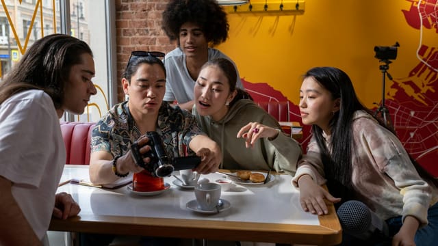 A diverse group of friends enjoying coffee and pastries together indoors.