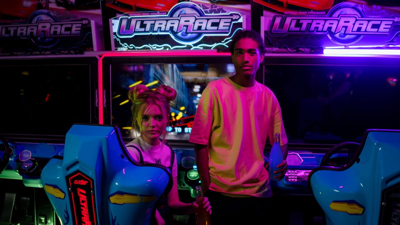 A young couple holding soda bottles in a vibrant arcade setting with neon lights.