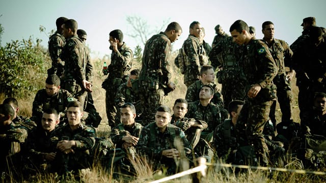 Group of soldiers taking a break outdoors in military uniforms, showcasing camaraderie.