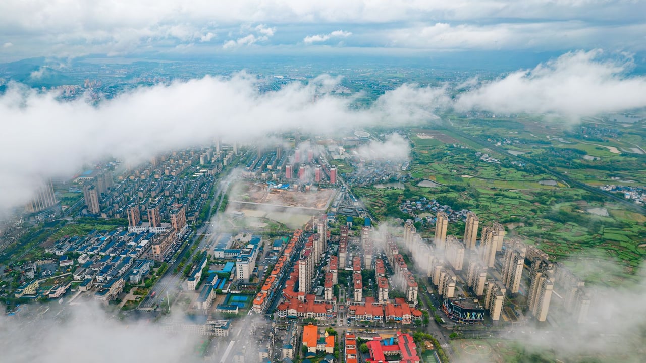 Stunning aerial cityscape with skyscrapers and lush fields seen through passing clouds.
