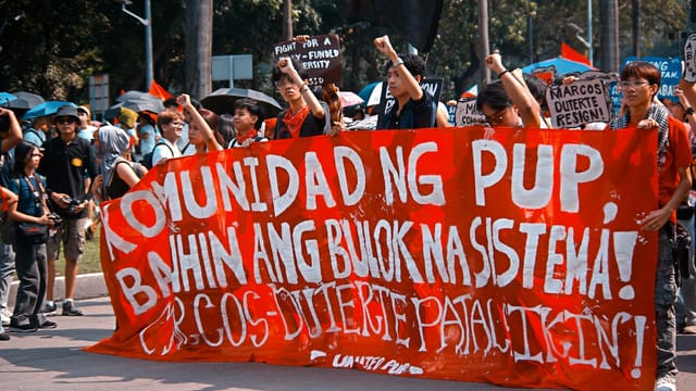 Demonstration in Manila advocating systemic change. Engaged crowd holding banners and signs.