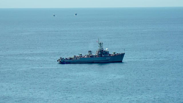 A military ship navigating the calm blue ocean under a clear sky, showcasing nautical power.