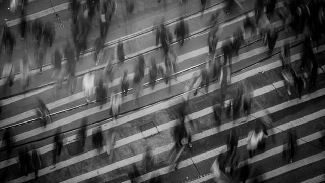 Blurred pedestrians crossing a busy Hong Kong street, showcasing urban movement and dynamics.