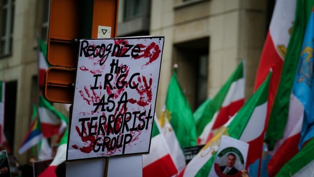 Protest in Brussels with flags and signs demanding IRGC recognition as a terrorist group.