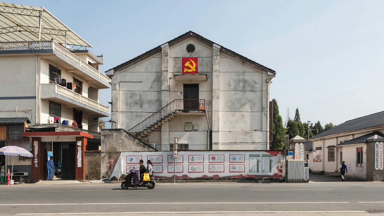 Exteriors of low level buildings decorated with hammer and sickle flag located in suburban area in Communist country