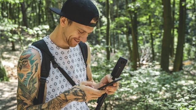 A person using a camera in a sunlit forest in Berlin, Germany, enjoying nature and exploration.