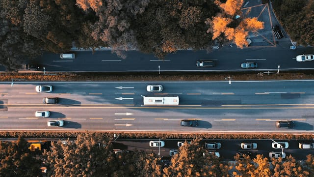 Drone shot of a busy road in Guangzhou, China, during autumn with cars and vibrant foliage.