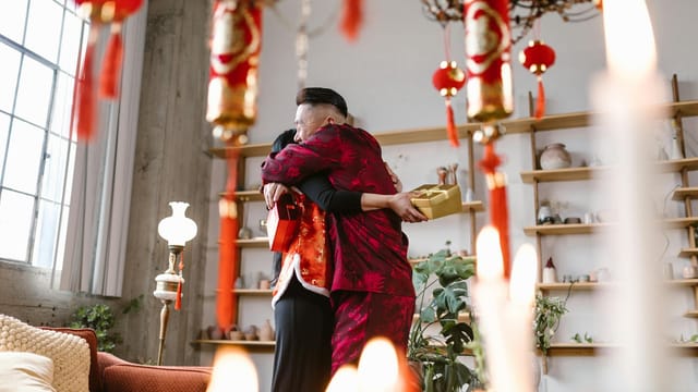 A heartwarming moment of two people embracing amidst Chinese New Year decorations indoors.