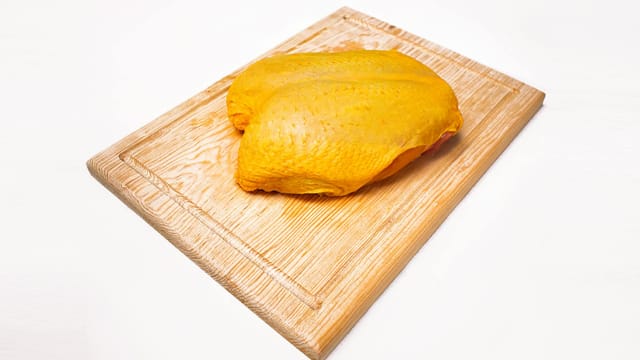 Uncooked chicken breast placed on a wooden cutting board, perfect for culinary needs.