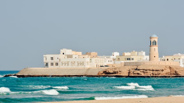 A serene view of Sur Lighthouse and traditional buildings on the Omani coast.