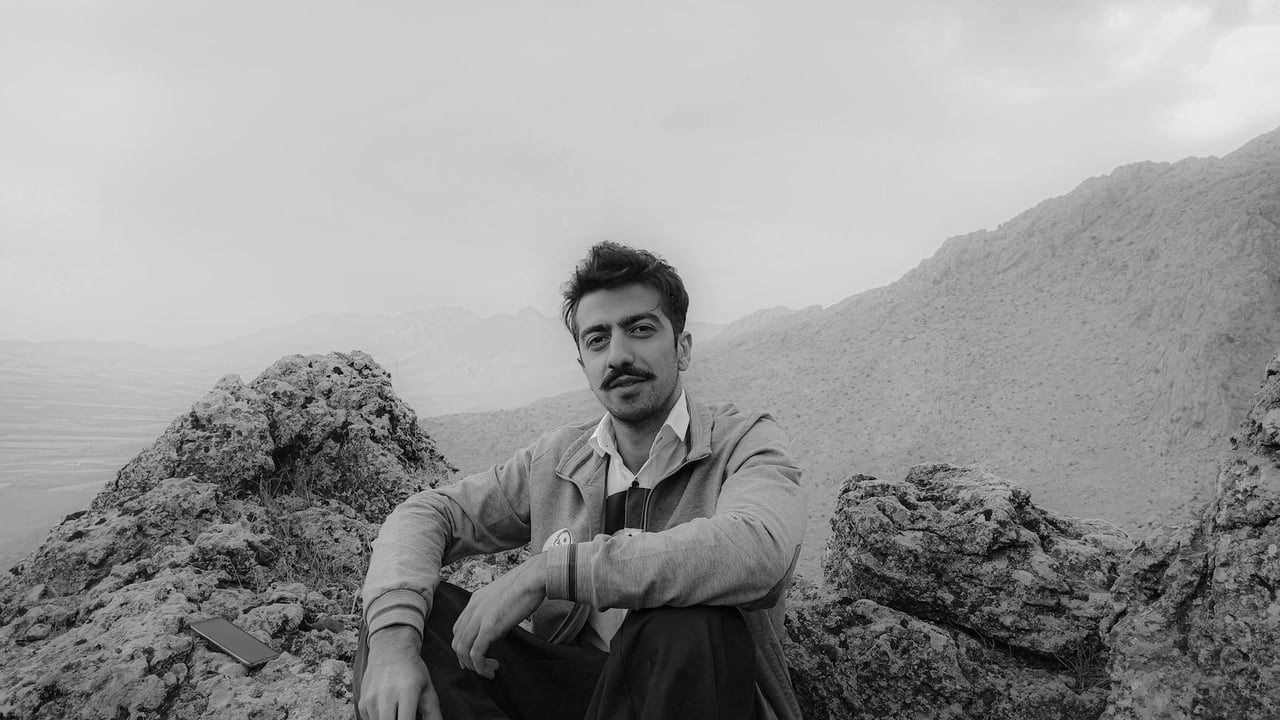 Monochrome photo of a man in Tehran's rugged mountains, capturing serene outdoor beauty.