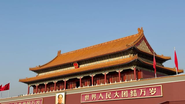Historic Tiananmen Gate under blue skies in Beijing, China, symbolic and tourist landmark.