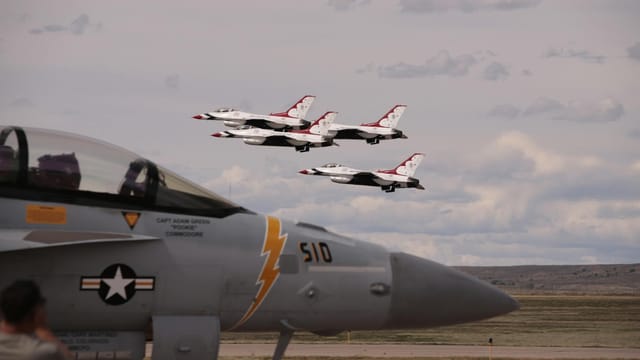 Four fighter jets perform a stunning aerial display in a clear sky, showcasing synchronized flight.