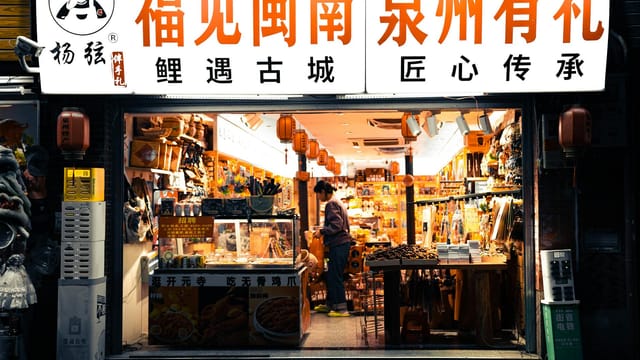 A bustling shopfront in a street market in Quanzhou, vividly lit and filled with local goods and lanterns.