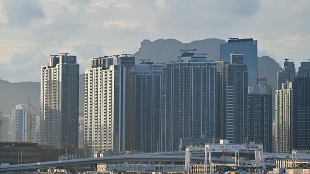 Cityscape featuring towering high-rise buildings against a mountainous backdrop.