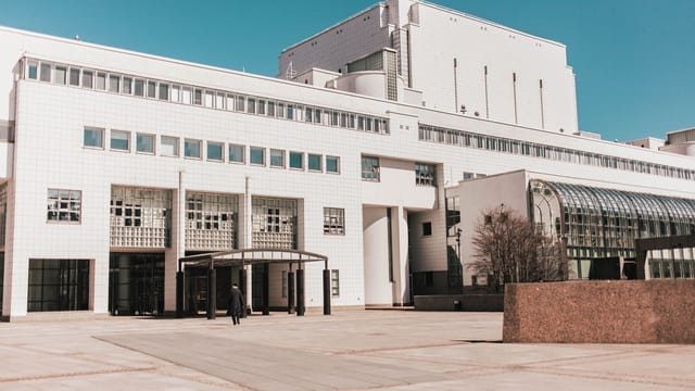 Exterior of contemporary building with huge number of various windows and and white walls on sunny pavement