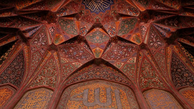 Colorful geometric patterns adorn the ceiling of a historic mosque in Lahore, showcasing Islamic art.