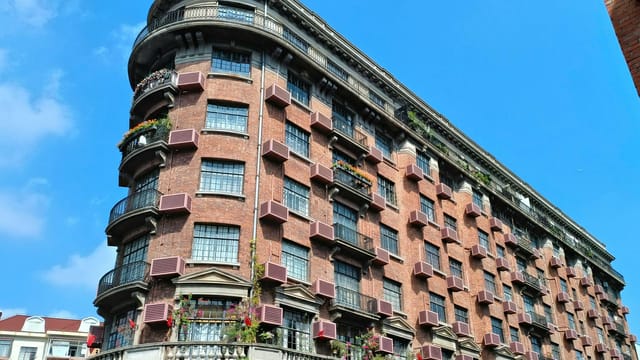 Elegant red-brick apartment building with blue sky background, showcasing classic architectural design.