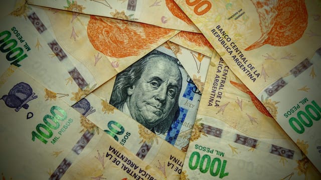 A detailed close-up of Argentinian pesos and a US dollar, showcasing currency contrast.