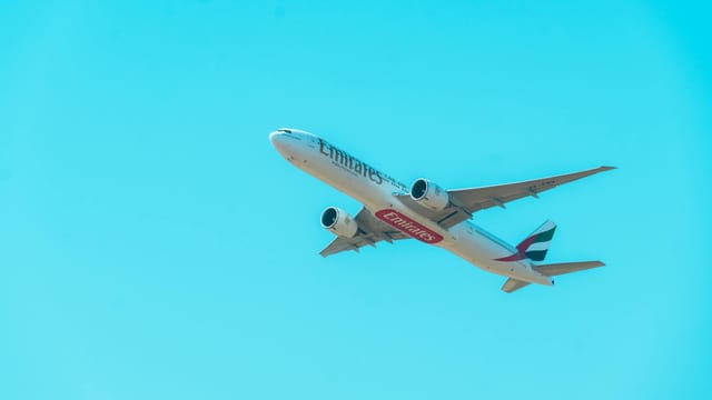 Emirates airplane flying high in a clear blue sky, showcasing modern air travel.
