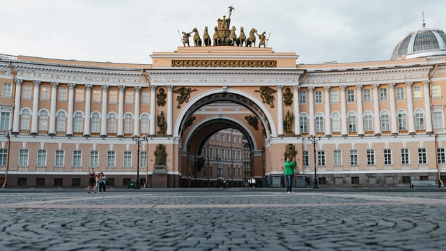 Historical architecture of General Staff Building in St. Petersburg's Palace Square with people and tourists.