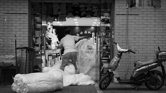 A street vendor organizes materials in a bustling Shanghai market, capturing urban life and vibrant local culture.