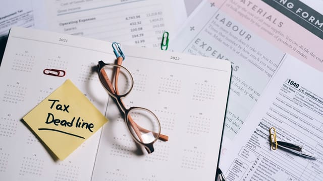 A calendar marked with "Tax Deadline" surrounded by financial documents and eyeglasses.
