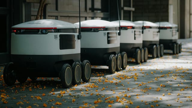 Futuristic delivery robots lined up outdoors, showcasing innovative modern technology.