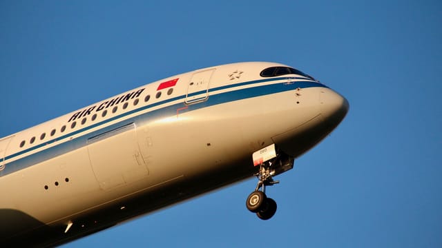 Close-up of an Air China passenger plane flying against a clear blue sky, showcasing aviation dynamics.