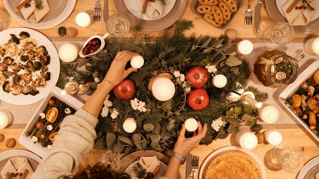 A top-down view of a festive holiday table setting with candles and decorations, perfect for Christmas or New Year's dinner.
