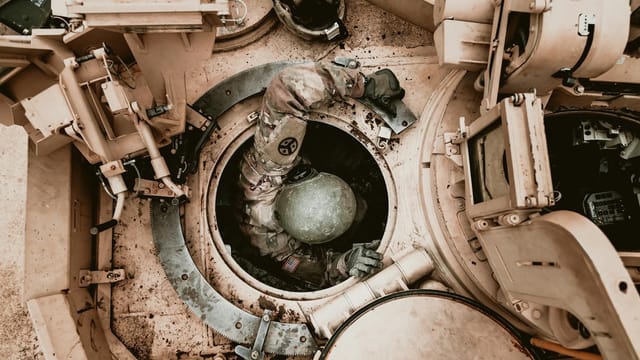 A soldier in protective gear enters an armored vehicle, showcasing readiness and technology.