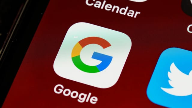 Macro view of a smartphone displaying Google and other app icons on the home screen.