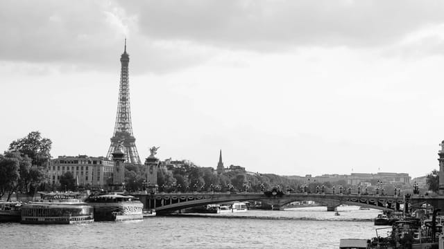 A classic black and white view of the Eiffel Tower over the Seine River in Paris, France.
