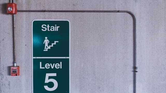 A fire alarm and stair sign on level 5 in an industrial indoor setting.