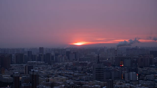 A breathtaking view of Harbin skyline with a vibrant sunset in the background.