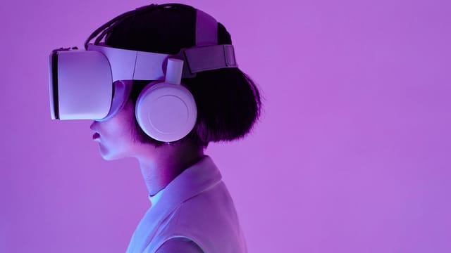 Side view of a woman wearing VR goggles in a purple-lit studio, highlighting modern technology.
