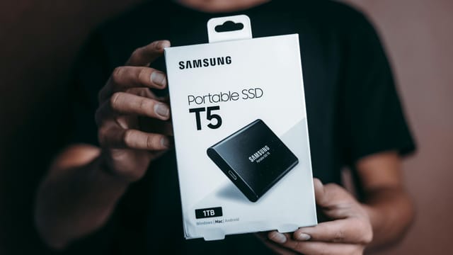 Close-up of a person holding a Samsung T5 Portable SSD box, emphasizing modern technology.