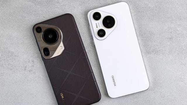 Top view of two Huawei smartphones, one black and one white, on a concrete surface.