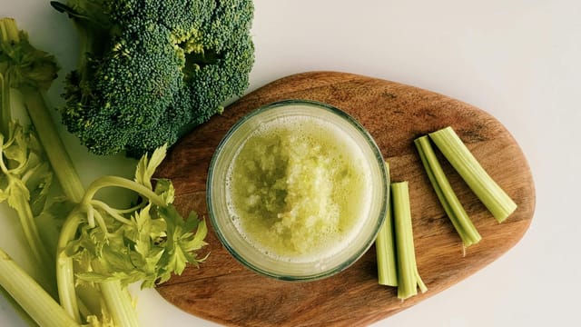 A refreshing green juice made from broccoli and celery, captured in a minimalist flat lay style.