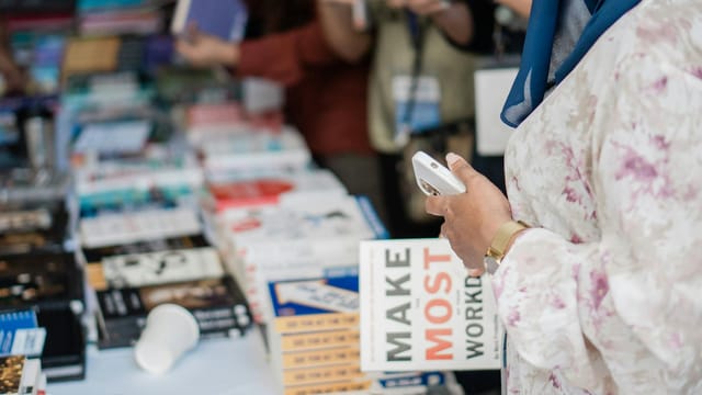 Close-up of various books on display at a book fair with attendees browsing.