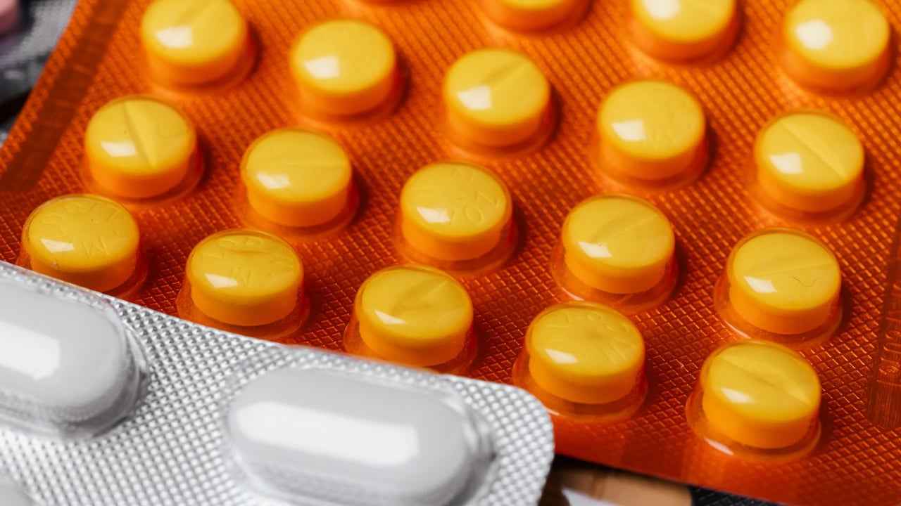 Closeup of multicolored assorted full plastic pills blister packs of different shape and size under bright light