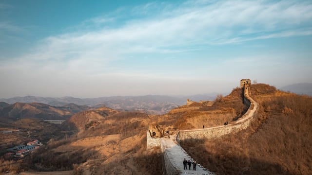 A scenic view of the Great Wall of China stretching across the rugged landscape under a clear blue sky.