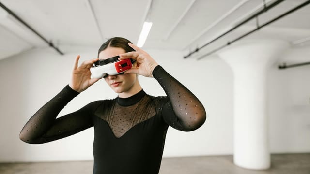 Elegant woman wearing VR glasses in a modern setting, exploring virtual worlds.