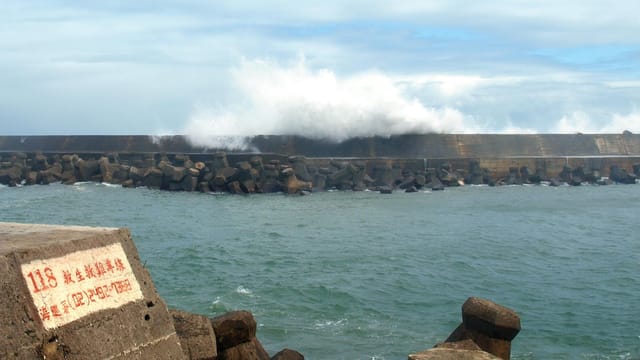 Powerful waves crash against the harbor wall in Wanli District, New Taipei City.