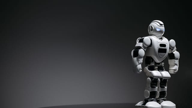 Compact humanoid robot toy standing on a reflective surface, exuding a futuristic vibe.