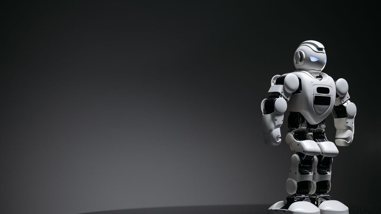 Compact humanoid robot toy standing on a reflective surface, exuding a futuristic vibe.